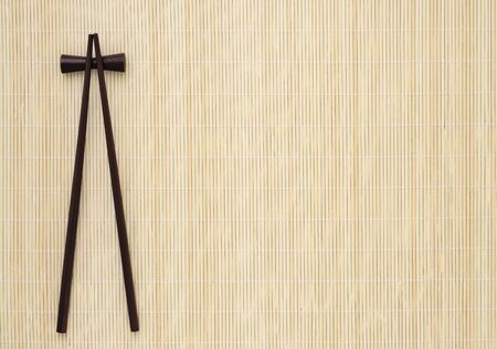 Bamboo mat with two dark brown sushi chopsticks の写真素材