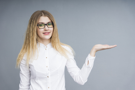 Young smiling business woman in a white shirt and glasses standing on the grey backgroundの写真素材