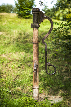 Old metal pump water in a garden, summer time.の写真素材