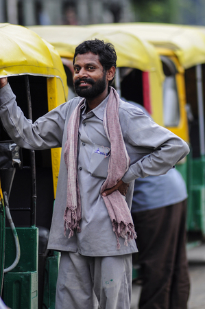 Delhi, India, september 2, 2010: Indian ricksaw tuk tuk man standing next to his tuk tuk.