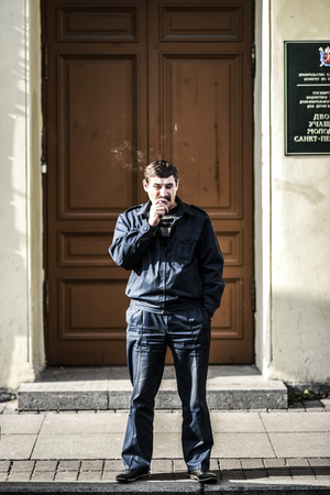 Petersburg, Russia, October 1, 2016: Man smoking cigarette in front of a door.のeditorial素材