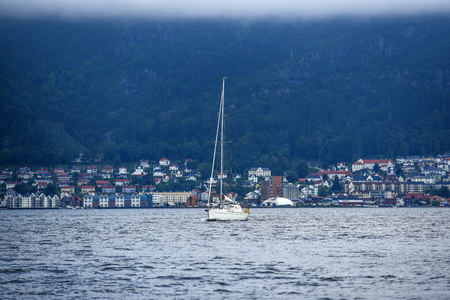 Coast of Norway, with yacht and charming cottages in the background, summer, cloudy sky.の写真素材