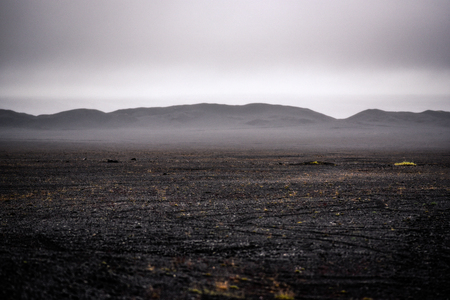 Iceland landscape, black volcanic dust and mountains with fog in background.の写真素材