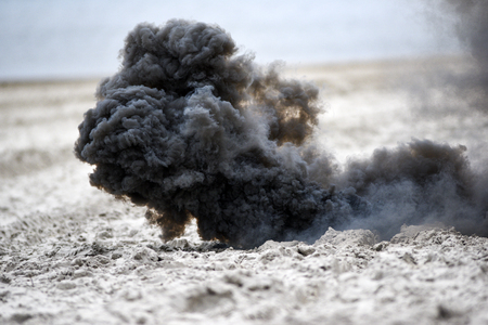 Explosion on the beach, billowing black smoke.の写真素材