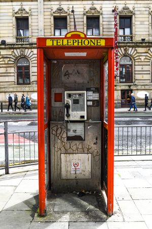 Dirty red telephone box in the city center in England.の写真素材