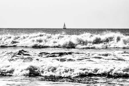 Sea landscape black and white, ocean waves with a yacht in the background, selective focus.の写真素材