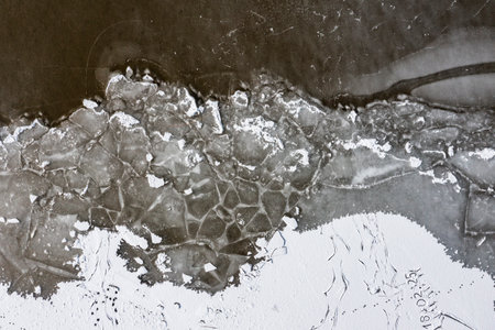 The texture of a frozen lake and pieces of floating ice in the water. Winter landscape from a drone.