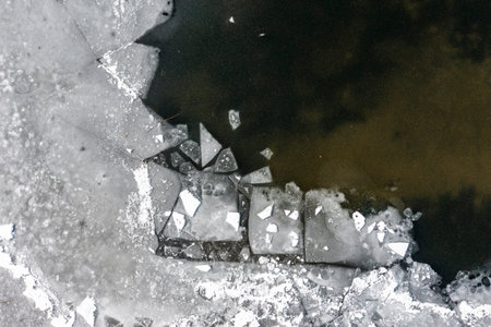 The texture of a frozen lake and pieces of floating ice in the water. Winter landscape from a drone.の写真素材