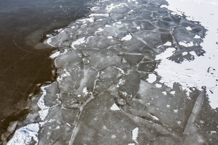 The texture of a frozen lake and pieces of floating ice in the water. Winter landscape from a drone.