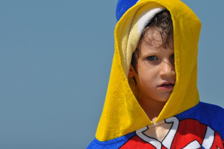The boy, a child in a towel and hood on the beachの写真素材