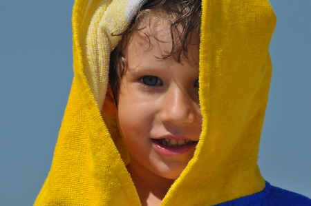 The boy, a child in a towel and hood on the beachの写真素材