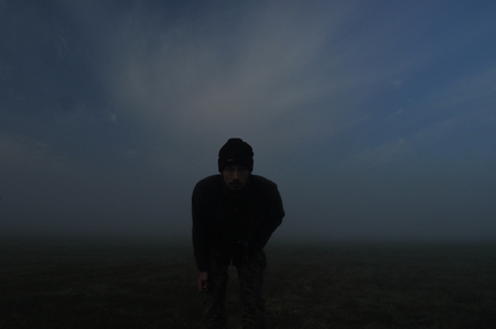 Man involved in sport in the morning. Meadow in the mist.