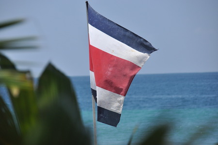 Flag of Costa Rica fluttering in the wind over the Pacific coast.の写真素材