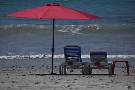 Sunbeds and umbrellas on the Adriatic coast, on a sandy beach in Italy. Rest and relaxation on holidays in a warm sunny country.の写真素材