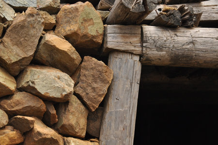 Close-up shows a combination of natural stone and rough timber used in building an aged structure. This setting reflects traditional craftsmanship and natural materials.の写真素材