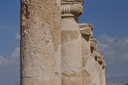 Stone columns rise majestically under a clear blue sky at an ancient site. The weathered structures intricately showcase details and tell stories of a long-lost civilization.の写真素材