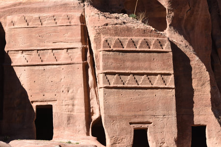 Ancient rock carvings on sandstone structures in a desert landscape. The carvings display intricately designs that reveal the artistry of a past civilization.の写真素材