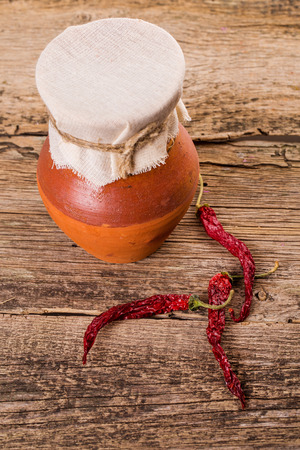 Old pitcher and red dry pepper on wooden tableの写真素材