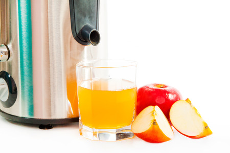 Juice extractor and freshly squeezed apple juice isolated on whiteの写真素材
