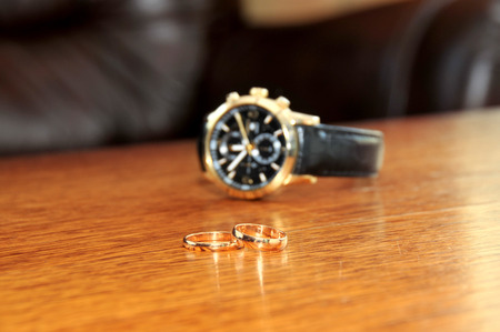 wedding ring and man watches on wooden the tableの写真素材