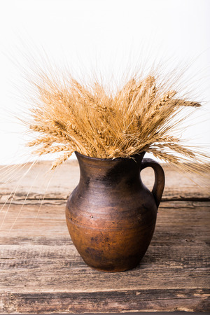 Rye spikelets in old pot on wooden の写真素材