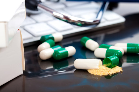 close-up green, white open medical capsules, (one opened), on black backgroundの写真素材