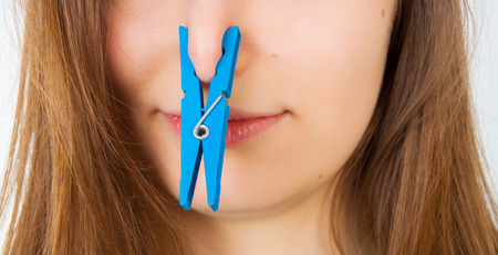 Portrait of young caucasian woman with Clothespin on her nose - bad smell conceptの写真素材