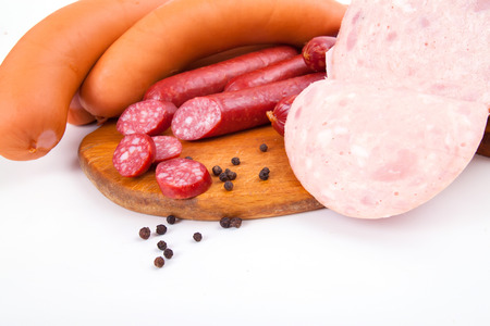 Different sorts of sausages on wooden desk and white background