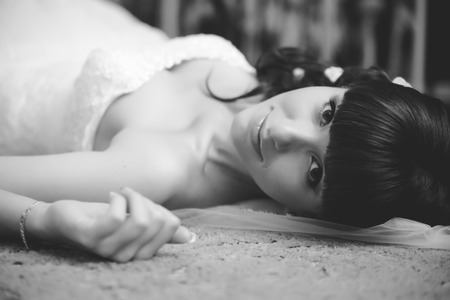 Gorgeous bride in wedding dress in luxury interior with diamond jewelry posing at home and waiting for groom. Romantic rich happy girl in bridal dressの写真素材