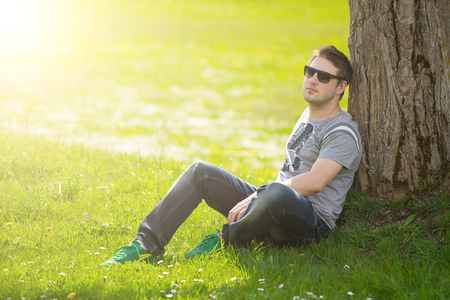 Intimate portrait of man with sunglasses outside in a park.の写真素材