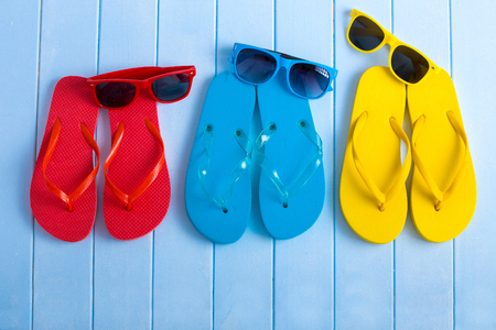 Colored Flip flops, with sunglasses on blue wooden piereの写真素材