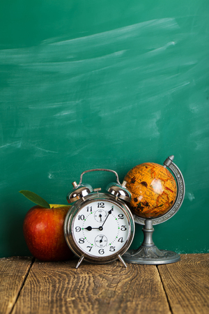 alarm clock, apple and globe on school desk backgroundの写真素材