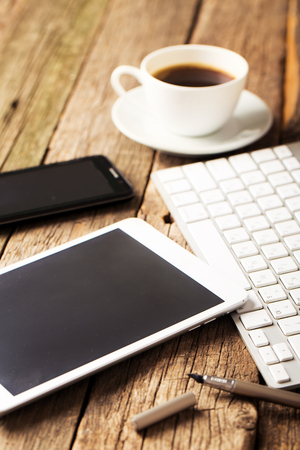 Office concept. Keyboard, tablet pc, and coffee on old wooden tableの写真素材
