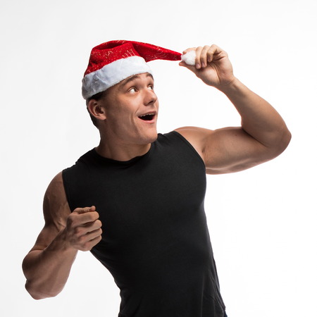 athlete bodybuilder posing with a beard and a cap of Santa Claus on a white backgroundの写真素材
