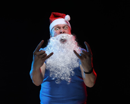 portrait actor male in cap and beard of Santa Claus with a sheet of paper for notes in the hands on a black backgroundの写真素材