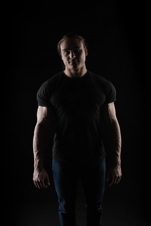 male bodybuilder athlete in the studio on a black background