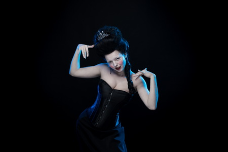 brunette woman with high hair and a corset in old style on a black backgroundの写真素材