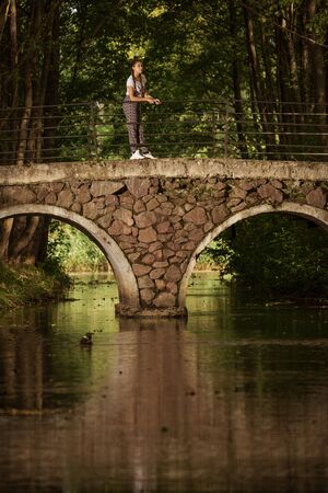 Emotional girl teenager with long hair hairstyle braids walks in the park at the waterfall on a sunny day.の写真素材