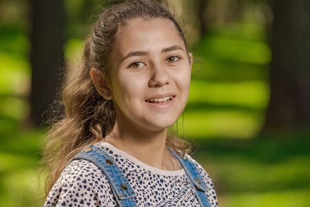 Emotional teenager girl with long hair in blue denim shorts walks in the park on a sunny day.の写真素材