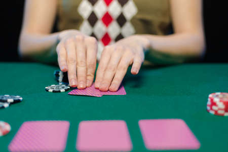 Female hands lay out playing cards and chips in a casino on a green tableの写真素材