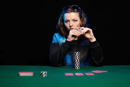 woman in blue clothes and sunglasses is playing cards in a casino on green cloth on a tableの写真素材