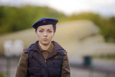 A young female pilot in uniform of Soviet Army pilots during the World War II. Military shirt with shoulder straps of a major and a beret. Against the background of a military aircraft.の写真素材