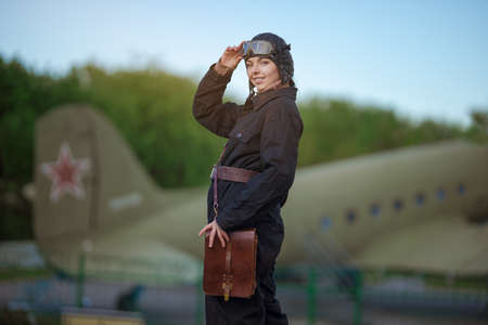 A young female pilot in uniform of Soviet Army pilots during the World War II. Black flying jumpsuit, helmet and goggles.の写真素材