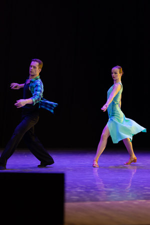 A pair of dancers a man and a woman perform in a theater on stage in a dance musical show.