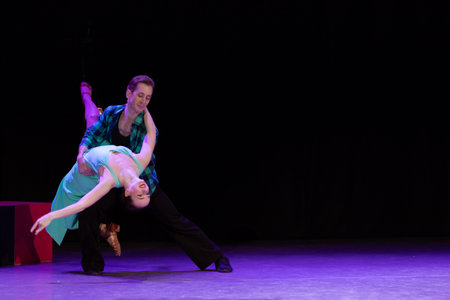 A pair of dancers a man and a woman perform in a theater on stage in a dance musical show.