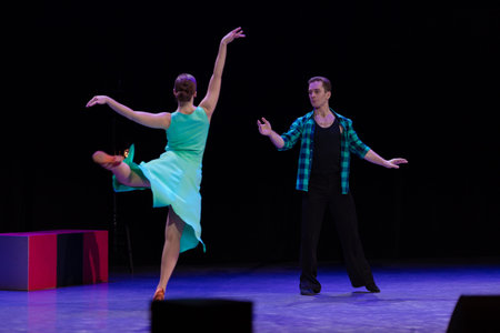A pair of dancers a man and a woman perform in a theater on stage in a dance musical show.