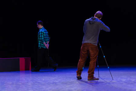 A pair of dancers a man and a woman are dancing on stage and a man videographer records a video clip and reports.の写真素材