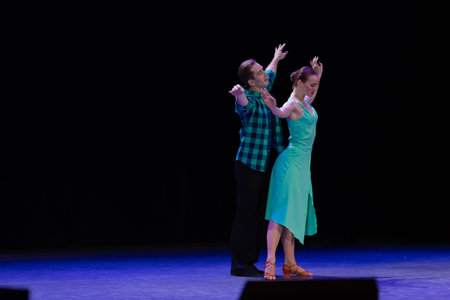 A pair of dancers a man and a woman perform in a theater on stage in a dance musical show.