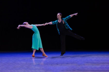 A pair of dancers a man and a woman perform in a theater on stage in a dance musical show.