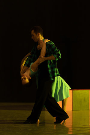A pair of dancers a man and a woman perform in a theater on stage in a dance musical show.